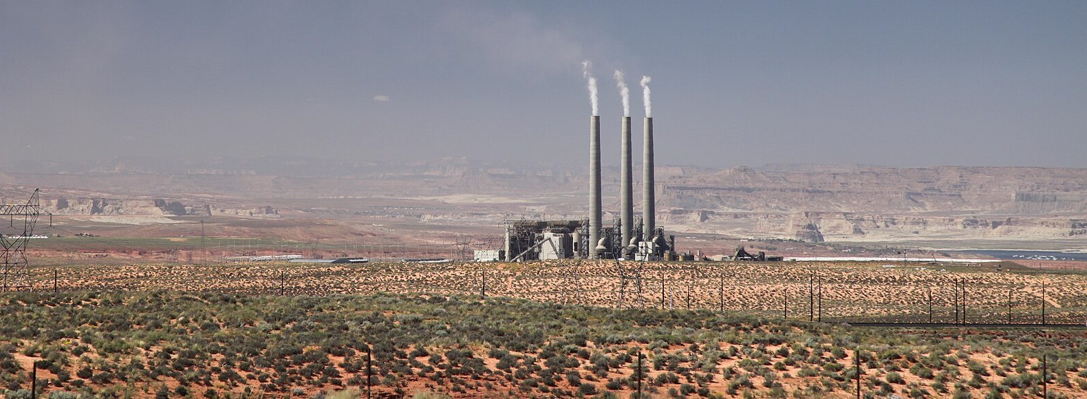 The Navajo Generating Station's three stacks rising from the Arizona desert near Page, red-rock mesas behind